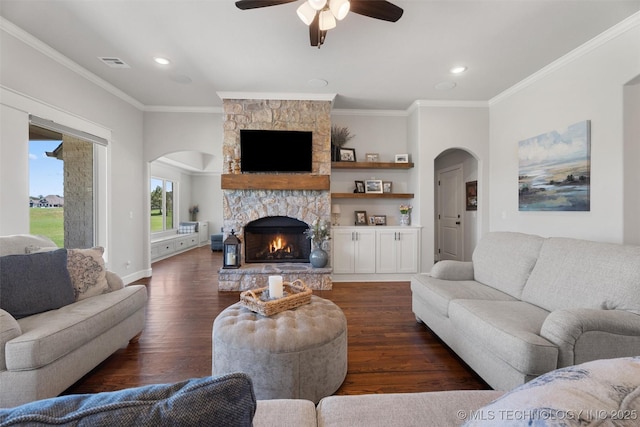 8209 N 150th Ave E, Owasso, OK 74055 - living room featuring arched walkways, dark wood-style flooring, ornamental molding, a ceiling fan, and a stone fireplace