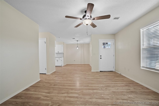 401 E 25th St, Okmulgee, OK 74447 - unfurnished living room with a ceiling fan, plenty of natural light, light wood-style flooring, and a textured ceiling