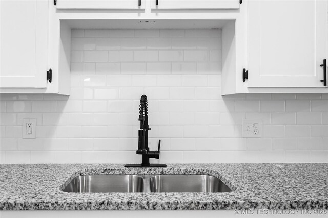 401 E 25th St, Okmulgee, OK 74447 - kitchen featuring a sink, backsplash, white cabinets, and light stone countertops