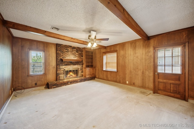 10925 E 4th St, Tulsa, OK 74128 - unfurnished living room featuring a textured ceiling, beamed ceiling, wood walls, ceiling fan, and a fireplace