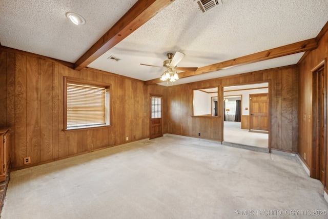 10925 E 4th St, Tulsa, OK 74128 - empty room featuring beamed ceiling, wood walls, a textured ceiling, a ceiling fan, and light colored carpet