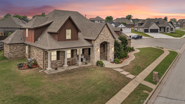 9512 N 144th E Ave, Owasso, OK 74055 - french country style house with stone siding, a shingled roof, concrete driveway, and a lawn