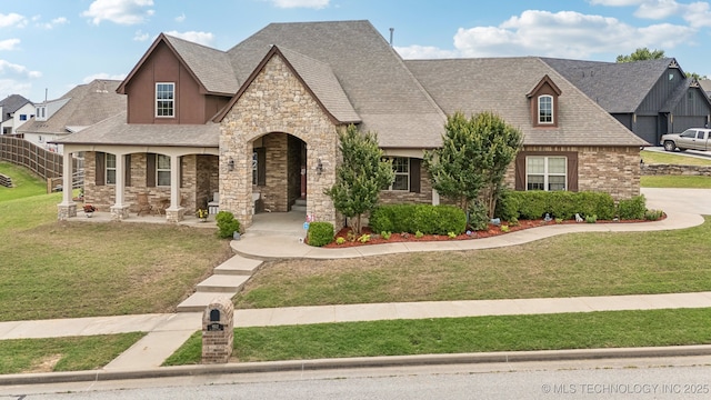 9512 N 144th E Ave, Owasso, OK 74055 - french country style house featuring stone siding, covered porch, a front lawn, and roof with shingles