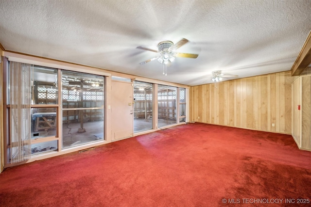 4921 E 26th St, Tulsa, OK 74114 - carpeted spare room with a ceiling fan, a textured ceiling, and wood walls