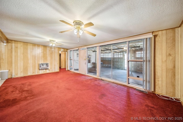 4921 E 26th St, Tulsa, OK 74114 - carpeted spare room featuring heating unit, wood walls, ceiling fan, and a textured ceiling