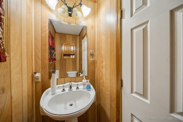 4921 E 26th St, Tulsa, OK 74114 - half bathroom featuring a chandelier, wooden walls, and a sink