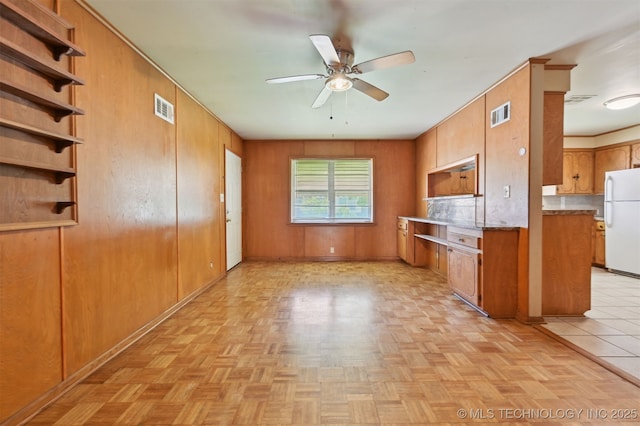 1604 E 55th Pl, Tulsa, OK 74105 - kitchen featuring freestanding refrigerator, ceiling fan, brown cabinetry, wood walls, and baseboards