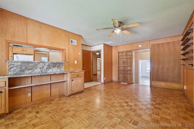 1604 E 55th Pl, Tulsa, OK 74105 - kitchen with a ceiling fan, wood walls, light stone countertops, and baseboards
