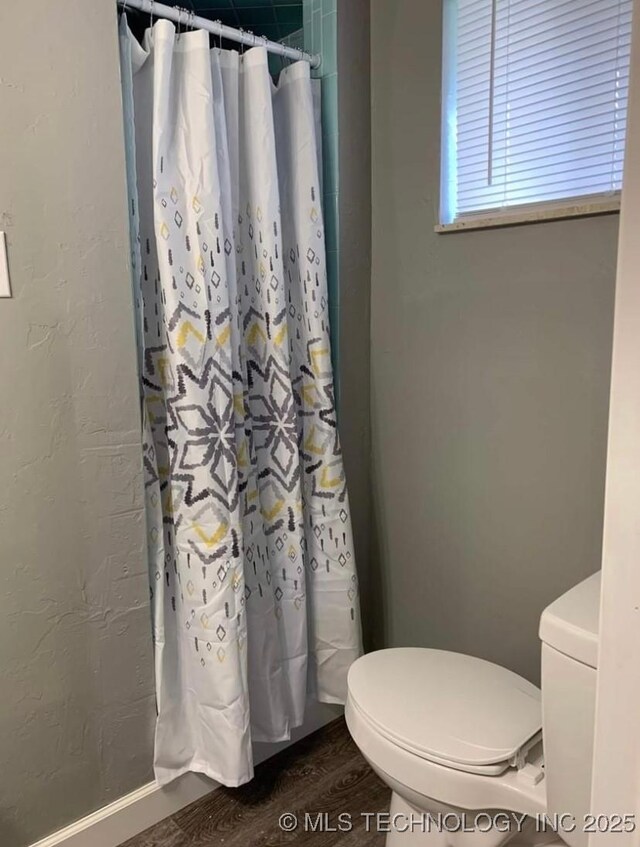 1011 E 11th St, Cushing, OK 74023 - bathroom featuring wood finished floors, toilet, and a shower with curtain