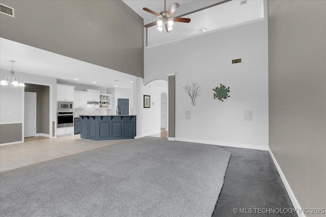 3000 S Tamarack Ave, Broken Arrow, OK 74012 - unfurnished living room featuring a towering ceiling, a ceiling fan, a sink, arched walkways, and a chandelier