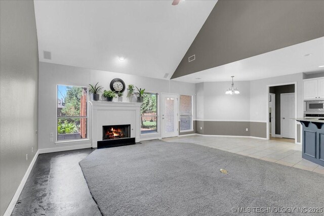 3000 S Tamarack Ave, Broken Arrow, OK 74012 - unfurnished living room featuring a fireplace with flush hearth, baseboards, a chandelier, high vaulted ceiling, and light tile patterned floors
