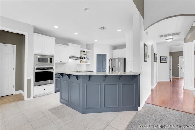 3000 S Tamarack Ave, Broken Arrow, OK 74012 - kitchen with appliances with stainless steel finishes, white cabinetry, under cabinet range hood, a peninsula, and a kitchen breakfast bar
