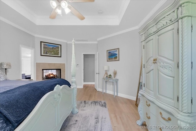 3000 S Tamarack Ave, Broken Arrow, OK 74012 - bedroom featuring light wood-type flooring, a raised ceiling, baseboards, a tiled fireplace, and ceiling fan