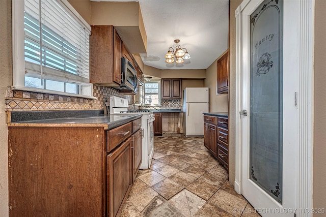 506 W 17th, Sulphur, OK 73086 - kitchen featuring white appliances, backsplash, a chandelier, dark countertops, and light stone finish flooring
