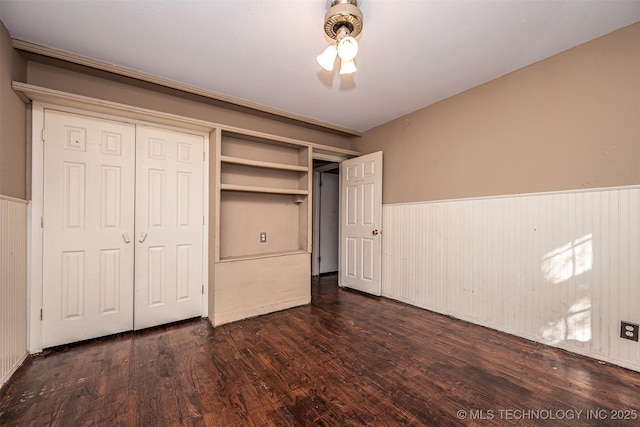 506 W 17th, Sulphur, OK 73086 - unfurnished bedroom with a wainscoted wall, dark wood-style flooring, and a closet