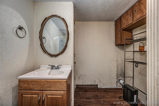 506 W 17th, Sulphur, OK 73086 - bathroom featuring wood finished floors, vanity, a textured wall, and a textured ceiling
