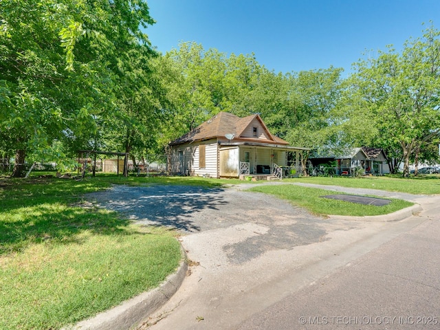 614 W 4th, Ada, OK 74820 - view of front of house with a porch, dirt driveway, and a front lawn