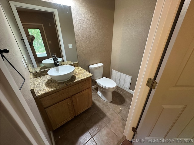 905 Brookside Dr, Durant, OK 74701 - bathroom featuring vanity, a textured wall, toilet, tile patterned floors, and baseboards