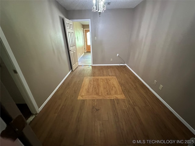 905 Brookside Dr, Durant, OK 74701 - unfurnished dining area featuring wood finished floors, baseboards, a textured ceiling, and a chandelier