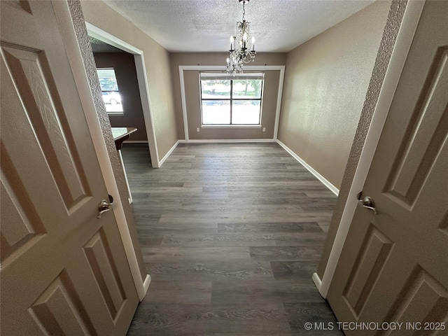 905 Brookside Dr, Durant, OK 74701 - empty room featuring a textured ceiling, a chandelier, baseboards, dark wood-style flooring, and a textured wall