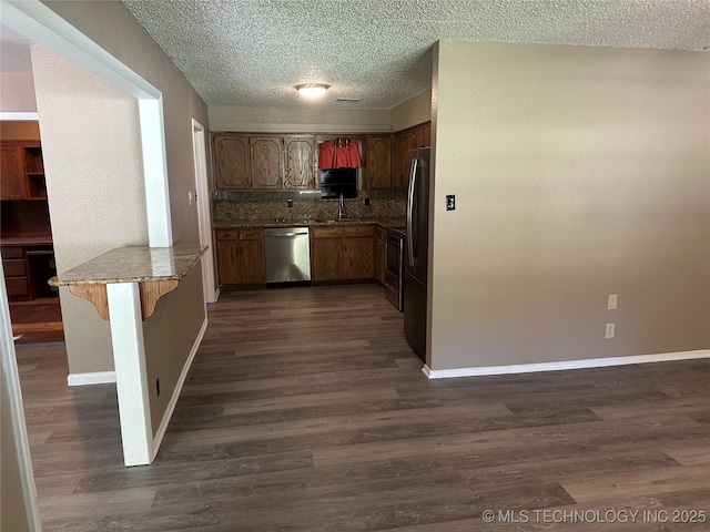 905 Brookside Dr, Durant, OK 74701 - kitchen with stainless steel appliances, a peninsula, dark wood-type flooring, baseboards, and a textured ceiling