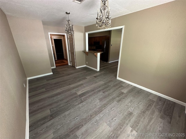 905 Brookside Dr, Durant, OK 74701 - unfurnished dining area with a chandelier, baseboards, dark wood-type flooring, and a textured ceiling