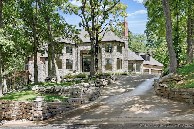 5011 E 84th St, Tulsa, OK 74137 - french country inspired facade featuring driveway, stone siding, a garage, and a chimney