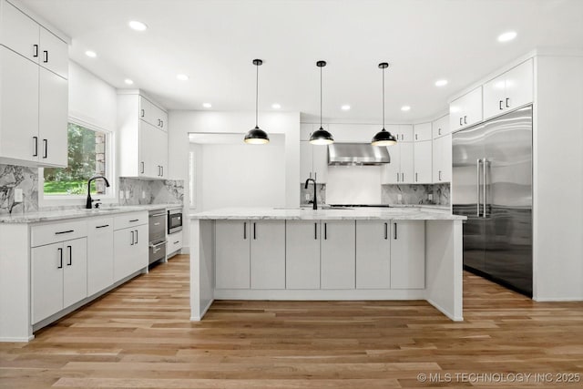5011 E 84th St, Tulsa, OK 74137 - kitchen with built in appliances, wall chimney exhaust hood, tasteful backsplash, white cabinetry, and light wood-style flooring