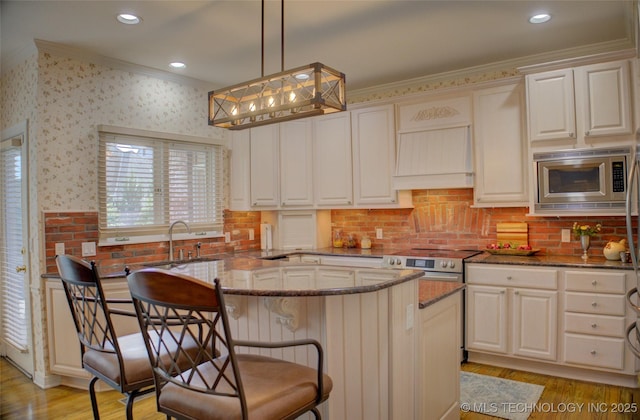 5140 E 107th Pl, Tulsa, OK 74137 - kitchen featuring ornamental molding, stainless steel appliances, dark stone counters, light wood finished floors, and a kitchen breakfast bar