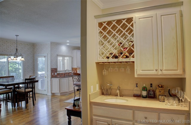 5140 E 107th Pl, Tulsa, OK 74137 - indoor wet bar with wallpapered walls, healthy amount of natural light, ornamental molding, decorative light fixtures, and light wood finished floors