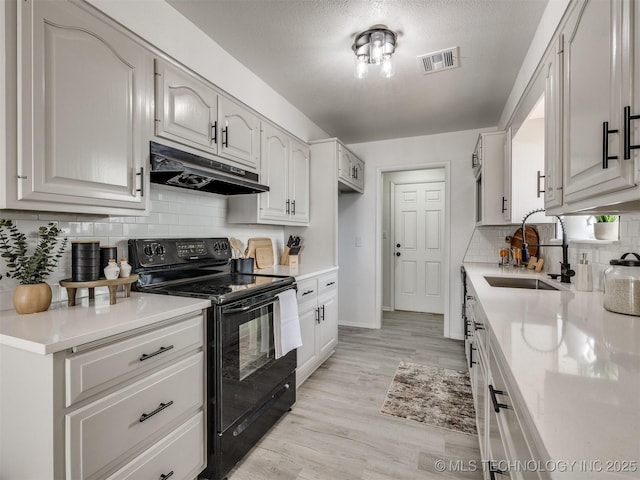 5015 S 89th E Pl, Tulsa, OK 74145 - kitchen with black / electric stove, under cabinet range hood, decorative backsplash, light wood finished floors, and white cabinets