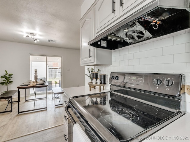 5015 S 89th E Pl, Tulsa, OK 74145 - kitchen with electric range, under cabinet range hood, wood finished floors, decorative backsplash, and white cabinetry