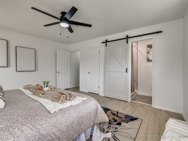 5015 S 89th E Pl, Tulsa, OK 74145 - bedroom with a barn door, light wood-style floors, ensuite bath, and ceiling fan