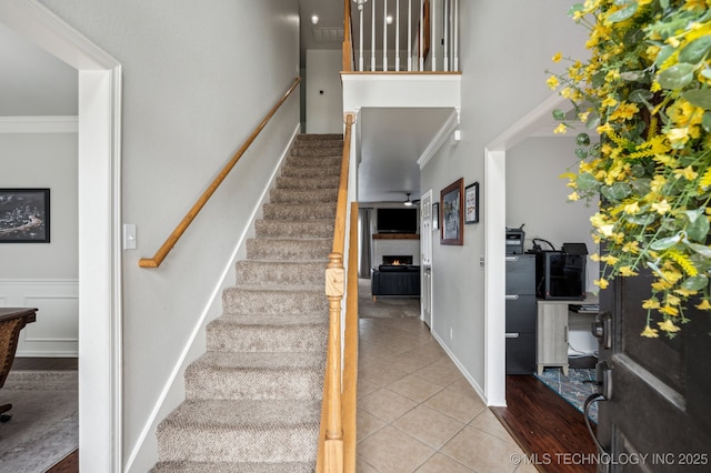 3305 N Oak Ave, Broken Arrow, OK 74012 - staircase with crown molding, a lit fireplace, and tile patterned flooring