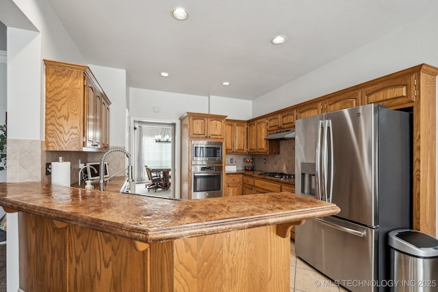 3305 N Oak Ave, Broken Arrow, OK 74012 - kitchen with stainless steel appliances, under cabinet range hood, a peninsula, tasteful backsplash, and recessed lighting