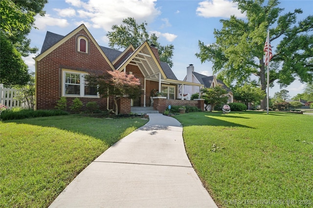 2403 S Troost Ave, Tulsa, OK 74114 - english style home featuring brick siding, a front lawn, and a chimney