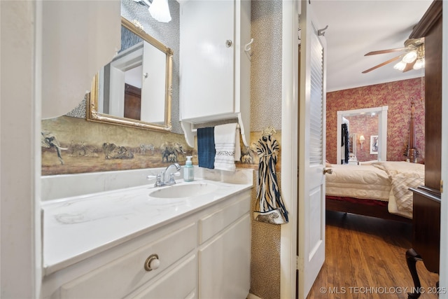 2403 S Troost Ave, Tulsa, OK 74114 - ensuite bathroom with wallpapered walls, wood finished floors, vanity, and ceiling fan
