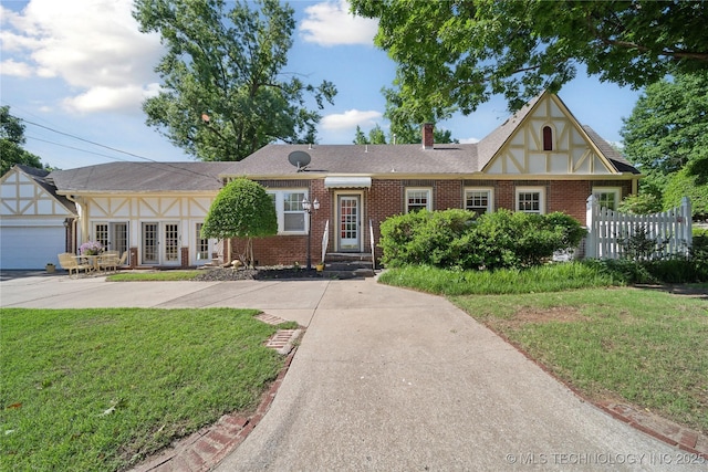 2403 S Troost Ave, Tulsa, OK 74114 - english style home with a front yard, brick siding, a chimney, and an attached garage