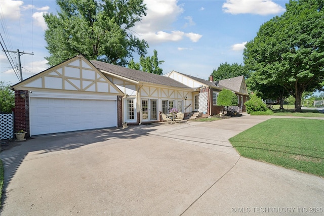2403 S Troost Ave, Tulsa, OK 74114 - view of front facade with driveway, brick siding, an attached garage, french doors, and a front lawn