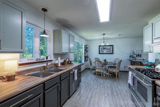 11787 S 4243rd Rd, Chelsea, OK 74016 - kitchen featuring stainless steel appliances, a sink, butcher block countertops, hanging light fixtures, and light wood-style flooring