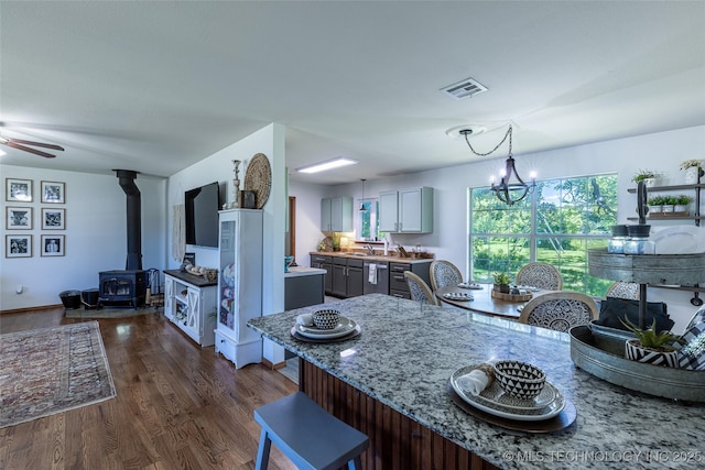 11787 S 4243rd Rd, Chelsea, OK 74016 - kitchen with a wood stove, dark wood-style flooring, a breakfast bar, light stone countertops, and gray cabinetry