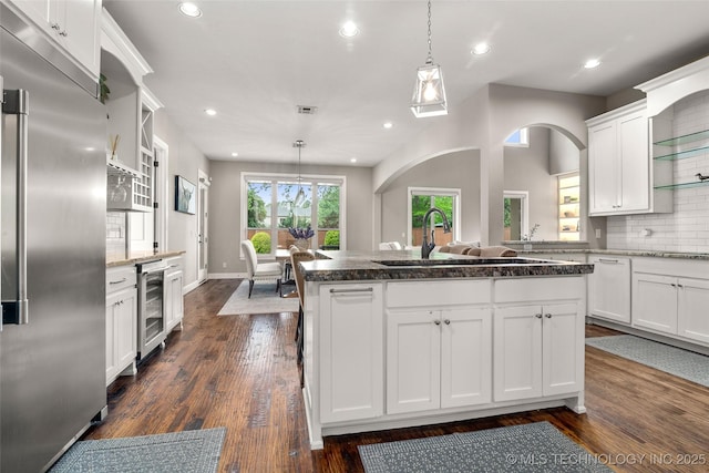 12014 S Kingston Pl, Tulsa, OK 74137 - kitchen with high quality fridge, a sink, arched walkways, beverage cooler, and white cabinetry