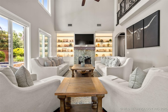 12014 S Kingston Pl, Tulsa, OK 74137 - living area featuring a towering ceiling, a stone fireplace, ceiling fan, arched walkways, and built in features