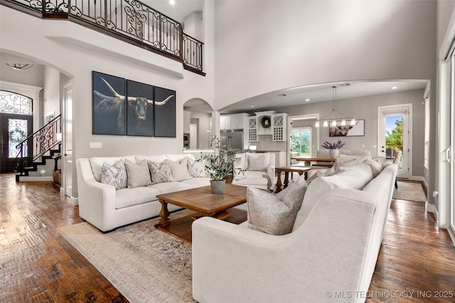 12014 S Kingston Pl, Tulsa, OK 74137 - living room featuring arched walkways, a high ceiling, hardwood / wood-style flooring, and baseboards