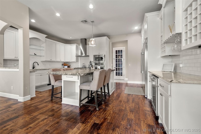 12014 S Kingston Pl, Tulsa, OK 74137 - kitchen featuring wall chimney exhaust hood, stainless steel appliances, decorative backsplash, beverage cooler, and a breakfast bar area