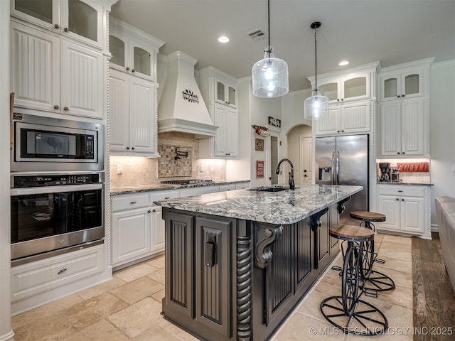 2915 E Rockford Pl, Broken Arrow, OK 74014 - kitchen with appliances with stainless steel finishes, a sink, custom range hood, stone tile flooring, and tasteful backsplash