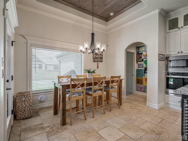 2915 E Rockford Pl, Broken Arrow, OK 74014 - dining area with a tray ceiling, stone tile flooring, arched walkways, baseboards, and a chandelier