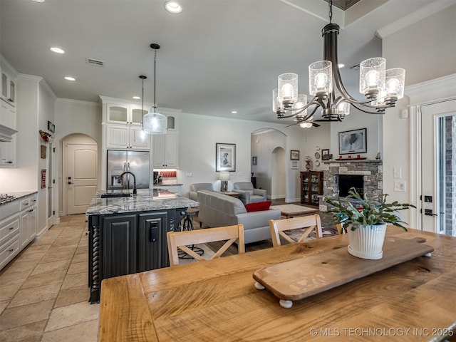 2915 E Rockford Pl, Broken Arrow, OK 74014 - dining room with arched walkways, recessed lighting, a chandelier, stone tile floors, and a fireplace