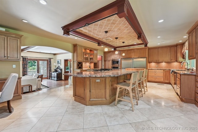 3898 E 72nd St, Tulsa, OK 74136 - kitchen featuring built in appliances, a center island, arched walkways, dark stone countertops, and recessed lighting
