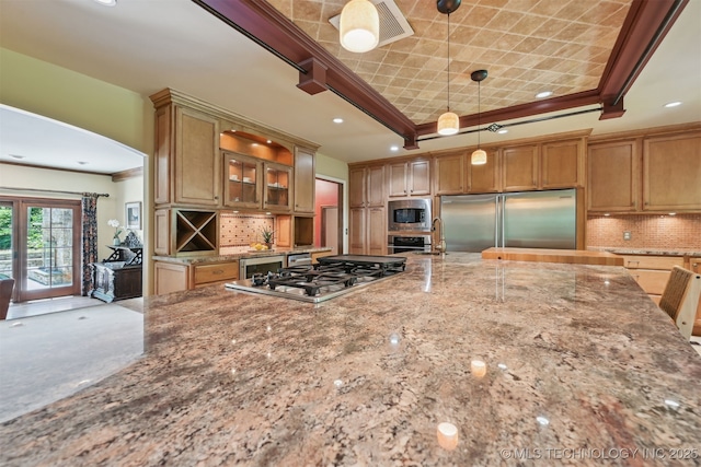 3898 E 72nd St, Tulsa, OK 74136 - kitchen with built in appliances, a tray ceiling, glass insert cabinets, light stone counters, and tasteful backsplash